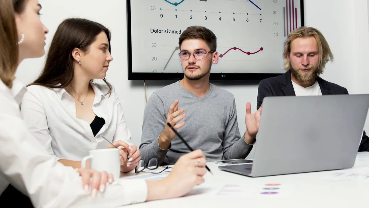 Echipă tânără dintr-un atelier social discutând în jurul unei mese de lucru